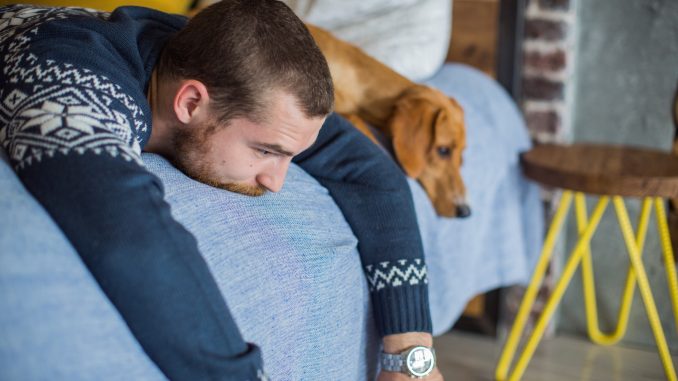 Young man laying on the bed with his dog. winter blues